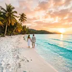 Pristine white sand beach in Vietnam with turquoise water and palm trees at sunset