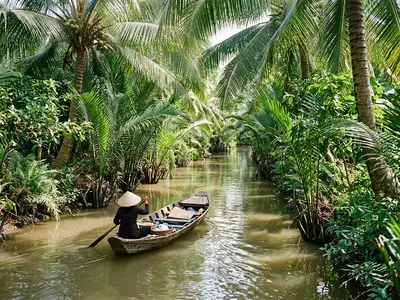 Narrow Mekong Delta canal lined with coconut palms and a sampan