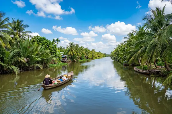 Mekong Delta canal with coconut palms and traditional sampan